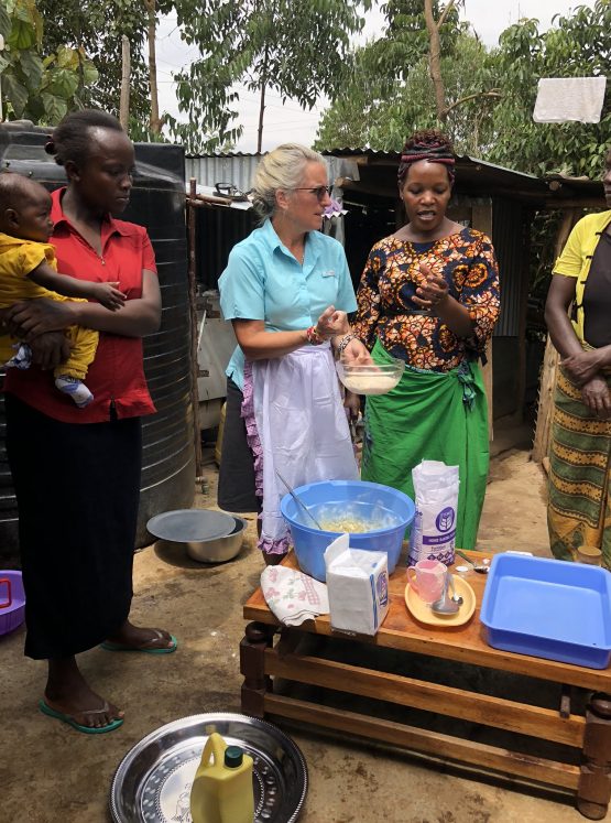 Kenya Hope team member partnering with local community members in Kenya. Helping make food while taking care of their babies